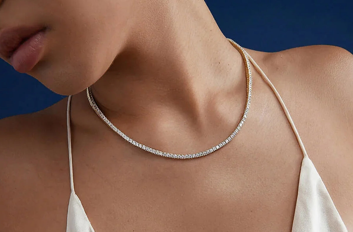 Gold tennis necklace worn along the collarbone