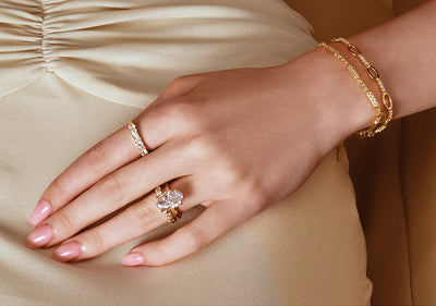 Hand wearing gold rings and bracelets
