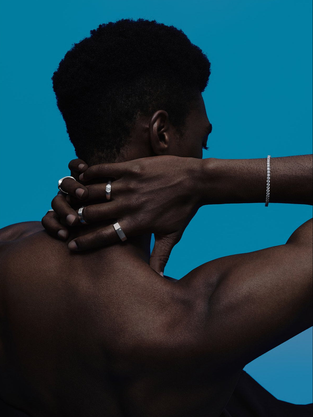 Man wearing men's rings and a tennis bracelet