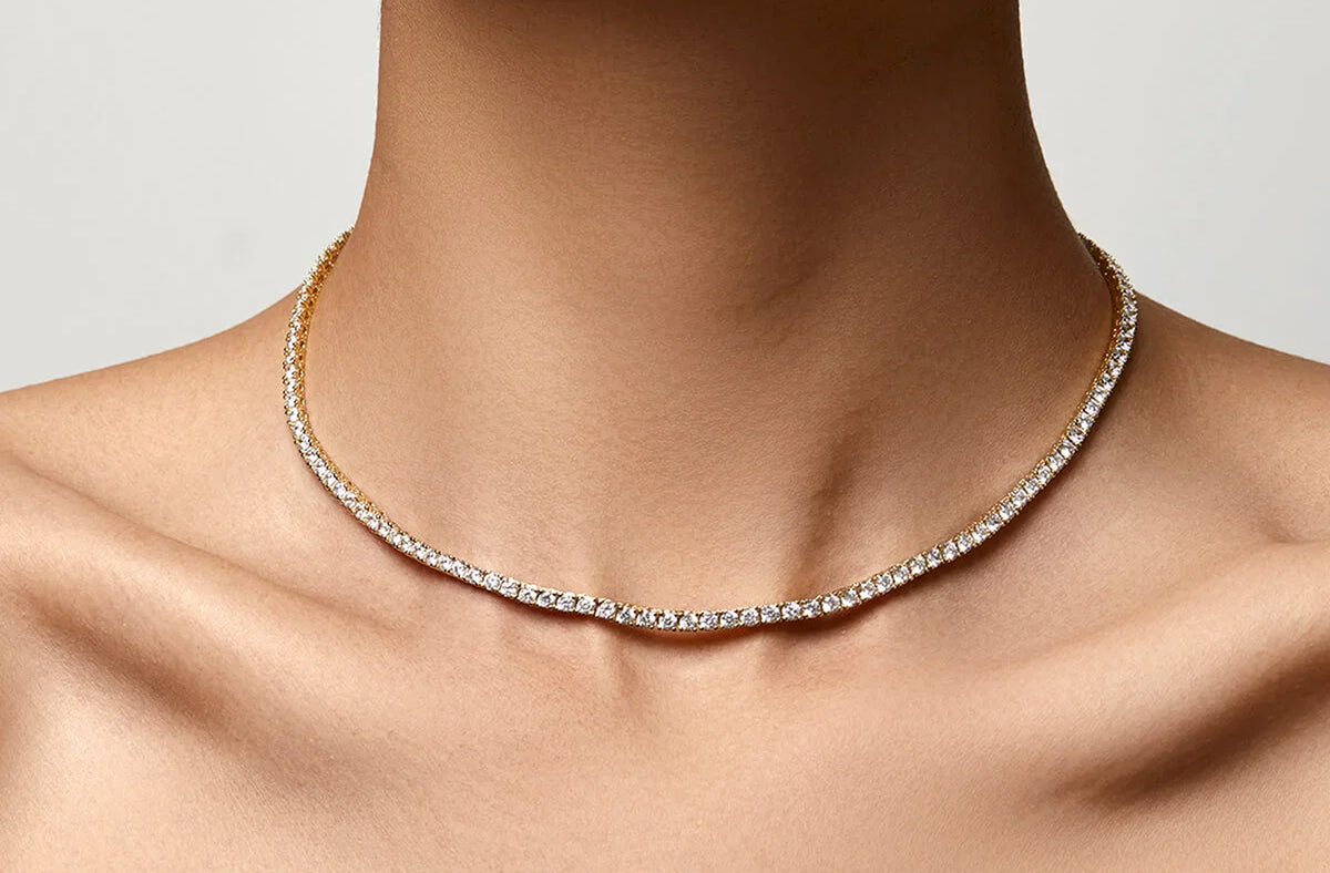 Gold tennis necklace lying flat on the collarbone