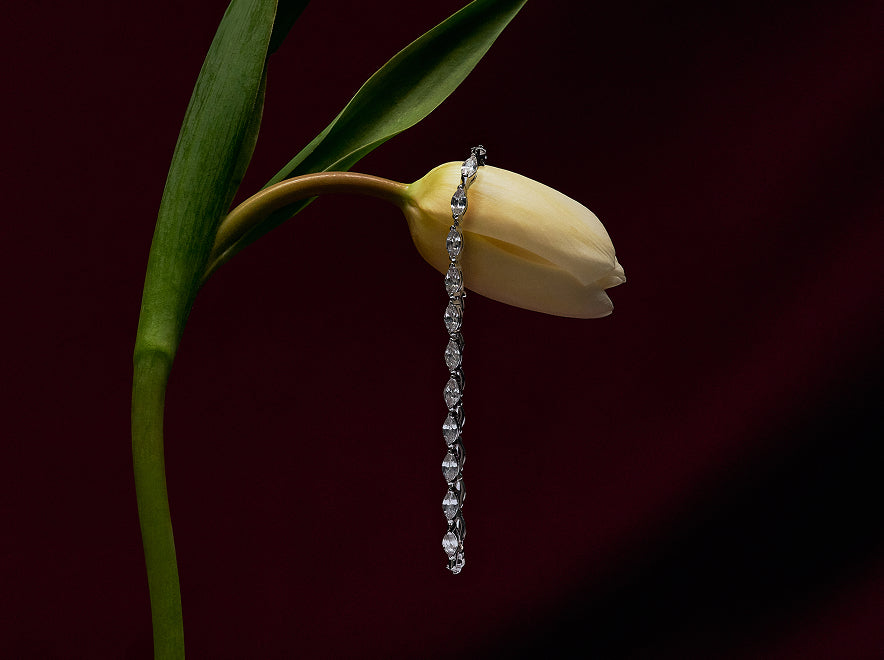 Silver tennis bracelet draped over a yellow tulip