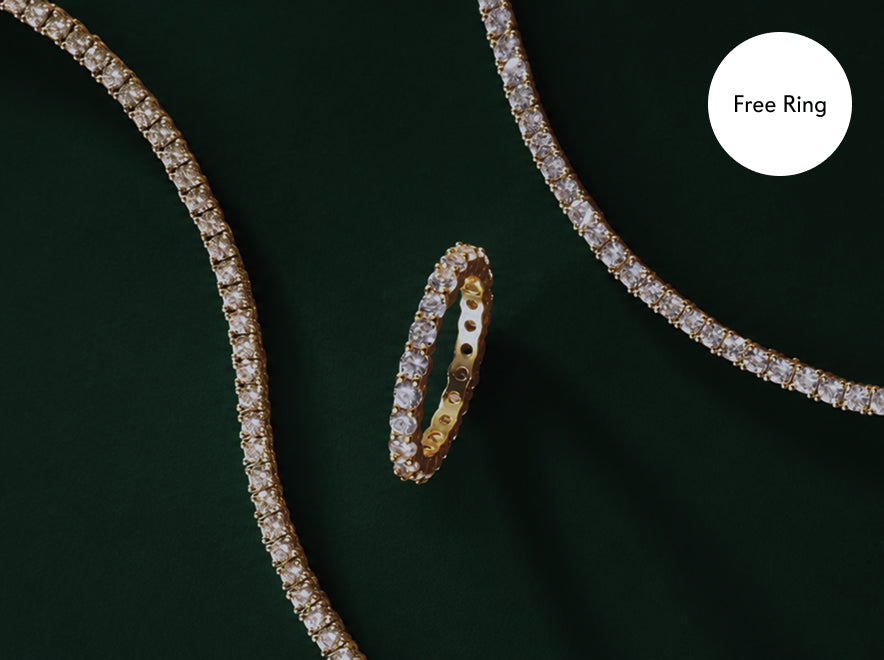 Gold tennis bracelet, necklace and ring set on green velvet