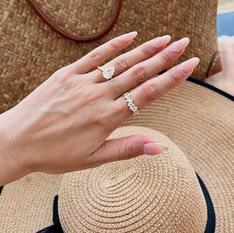 Hand with pear travel ring resting on a straw sun hat
