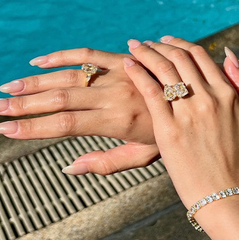 Two hands with travel rings and tennis bracelet at the pool edge