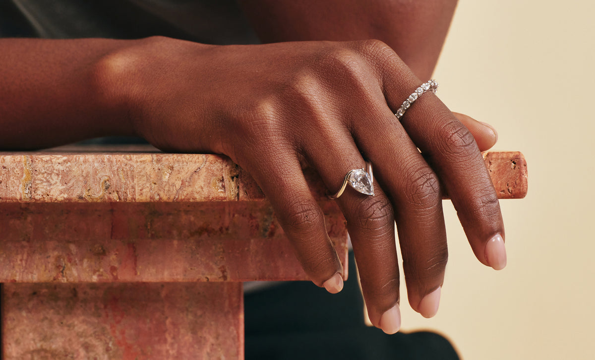 Hand wearing OBJKTS rings resting on a marble table