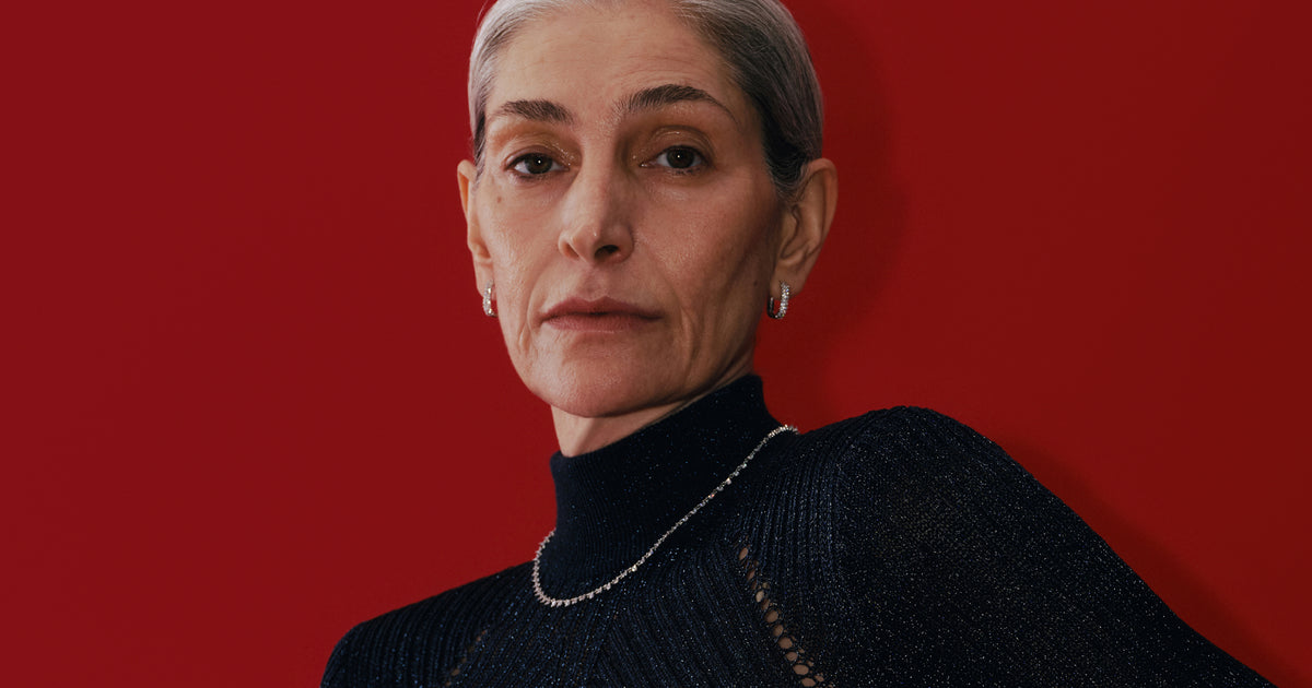 Model in a black knit wearing a tennis necklace and huggie earrings
